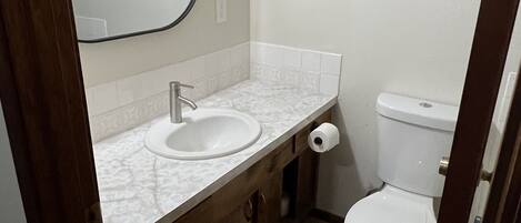 A bathroom with a white sink, mirror, and toilet.