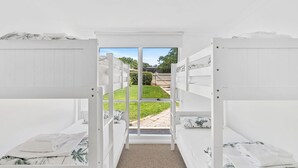 A room with bunk beds, a door leading outside, and a view of a grassy yard.