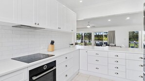 A modern kitchen with white cabinetry, a built-in oven, and a dishwasher.