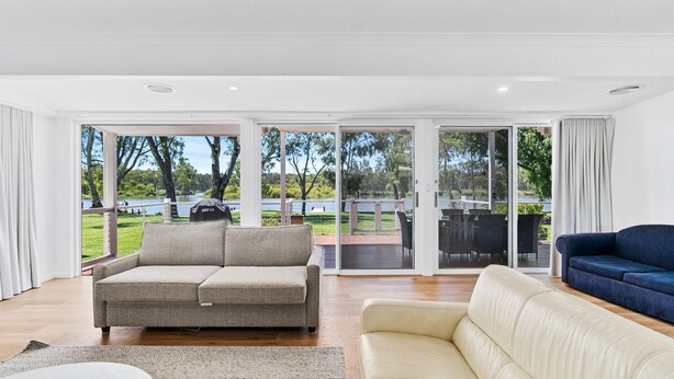 A spacious living room with a grey sofa, a blue sofa, and a beige sofa.