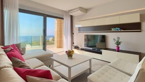 A modern living room with a sofa, coffee table, TV, and a balcony with a view. - Lovely home in Smrika (Smrika)