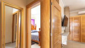 Un dormitorio con cama, armario de madera y televisor montado en la pared.