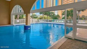 Una piscina interior con vistas despejadas a palmeras y edificios al exterior.