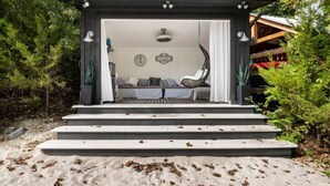 Un espacio de descanso al aire libre con techo, que incluye una silla colgante, un banco y una mesita.