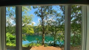 Una habitación con un ventanal que ofrece vistas a un lago rodeado de árboles.