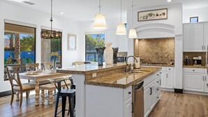 Uma cozinha moderna com bancadas de granito, armários brancos e iluminação pendente.