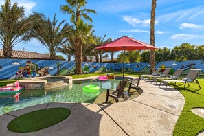 Une piscine avec des chaises longues et une fresque murale.