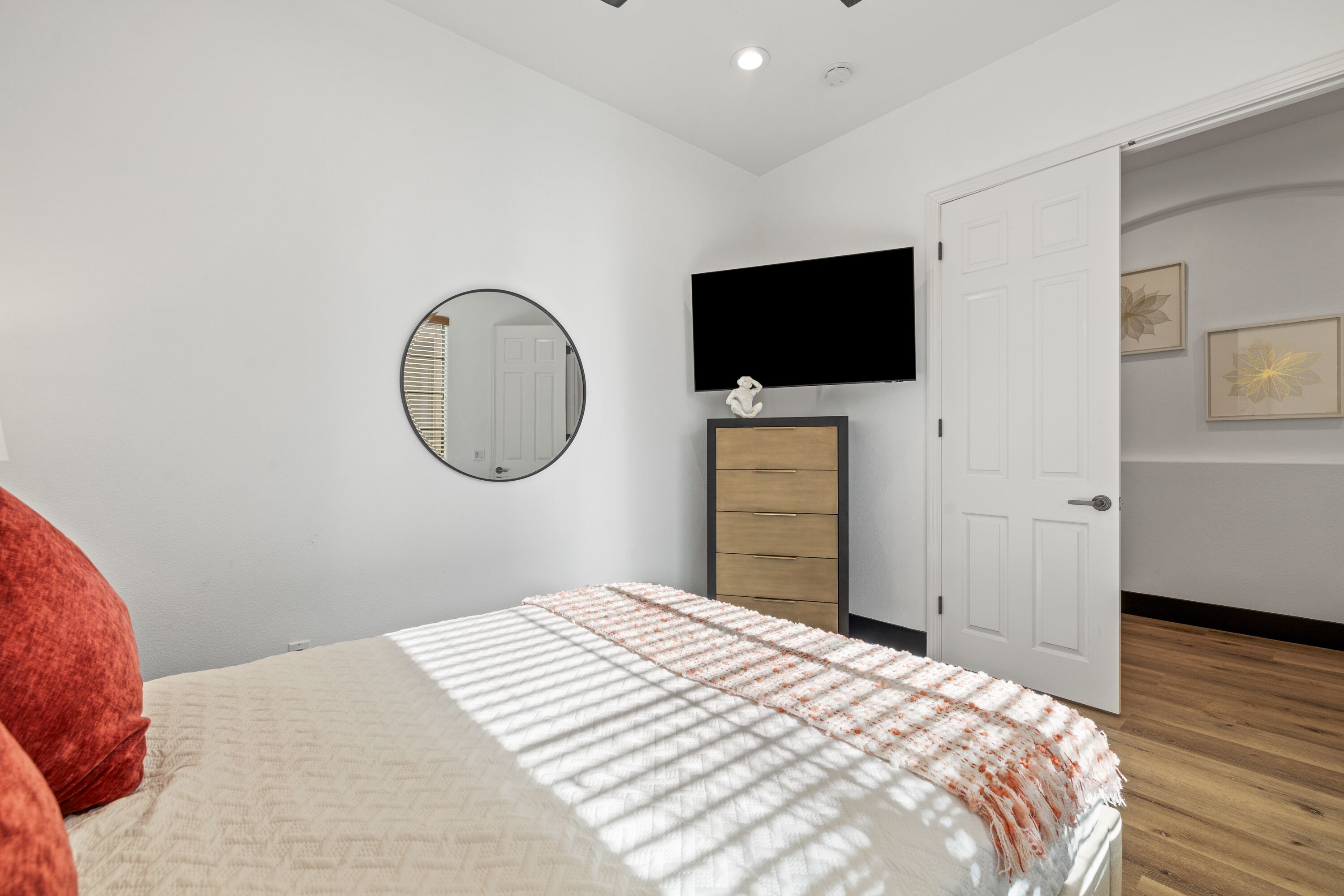 A bedroom with a bed, a dresser, a television, and a door.