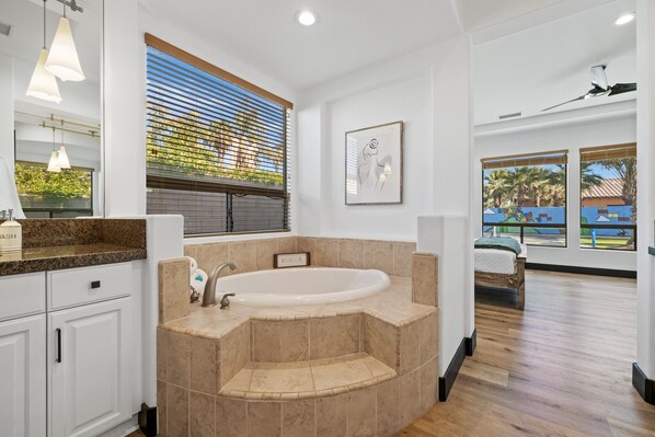 A modern bathroom with a freestanding bathtub, a large window with blinds, and a view of a playground. - Super Mario Hideout Desert Dream (Indio)