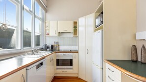 A compact kitchen with white cabinetry, a built-in oven, a microwave, and a sink. - The Nest - Central, Sunny & Spacious Loft (Te Aro)