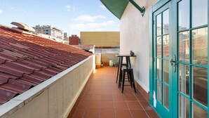 A rooftop terrace with a red-tiled roof, a green awning, and a blue door. - The Nest - Central, Sunny & Spacious Loft (Te Aro)