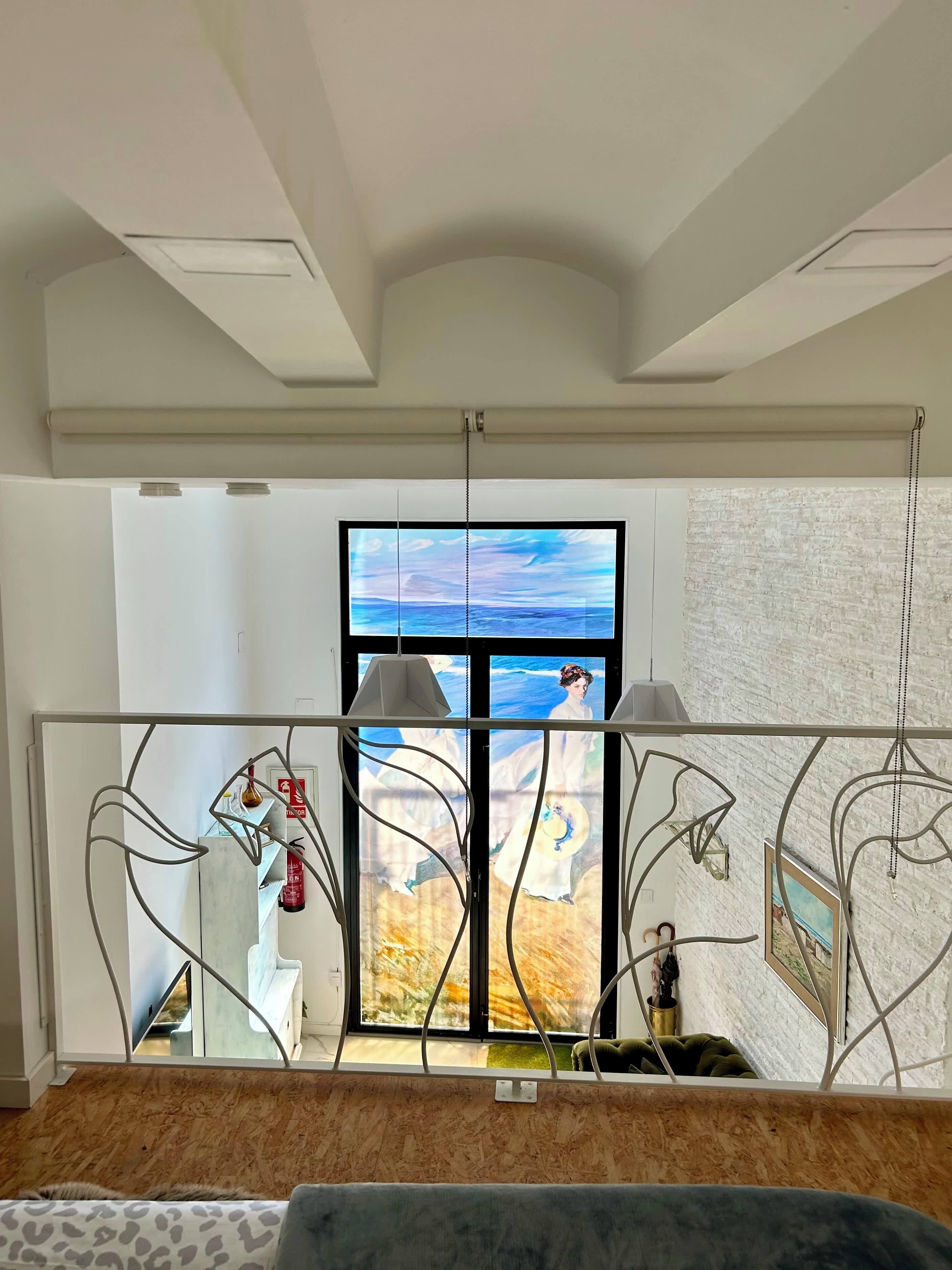 A modern interior with a large window, a metal railing, and a view of the outdoors.