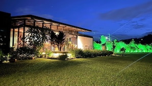 A modern building with a glass facade, surrounded by well-maintained lawns and illuminated green plants. - Beautiful Finca with Jacuzzi. Large green areas, surrounded by vegetation. (Rionegro)
