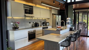 A modern kitchen with a central island, built-in appliances, and a view to the outdoors. - Beautiful Finca with Jacuzzi. Large green areas, surrounded by vegetation. (Rionegro)