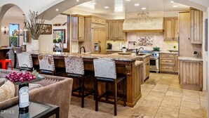 A spacious kitchen with wooden cabinets, a large island, and a dining area with a sofa and chairs. - Tuscan Style Wine Country Getaway (Paso Robles)