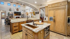 A spacious kitchen with wooden cabinetry, a large island, and a built-in oven. - Tuscan Style Wine Country Getaway (Paso Robles)