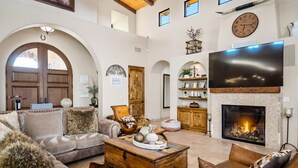 A spacious living room with a fireplace, comfortable seating, and a large TV. - Tuscan Style Wine Country Getaway (Paso Robles)