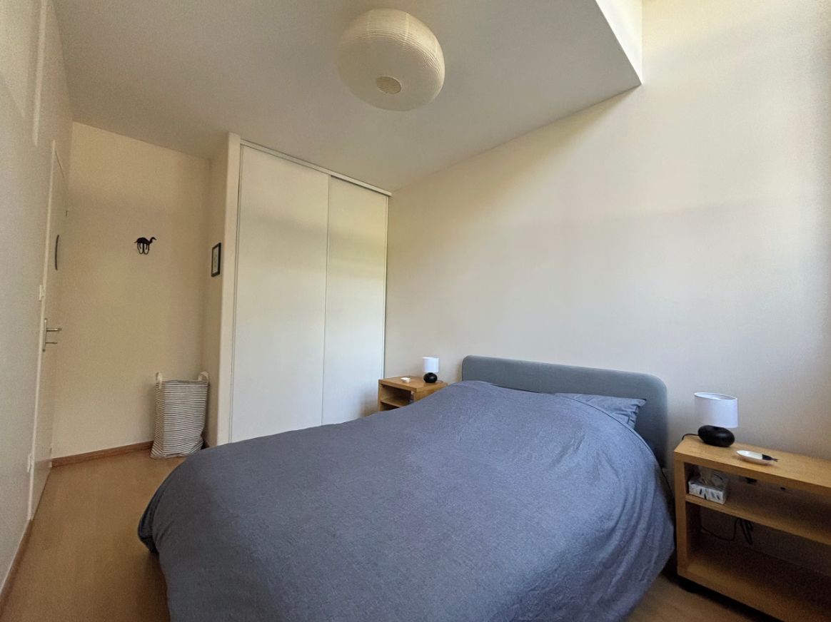 A bedroom with a bed, bedside tables, a wardrobe, and a ceiling light fixture.
