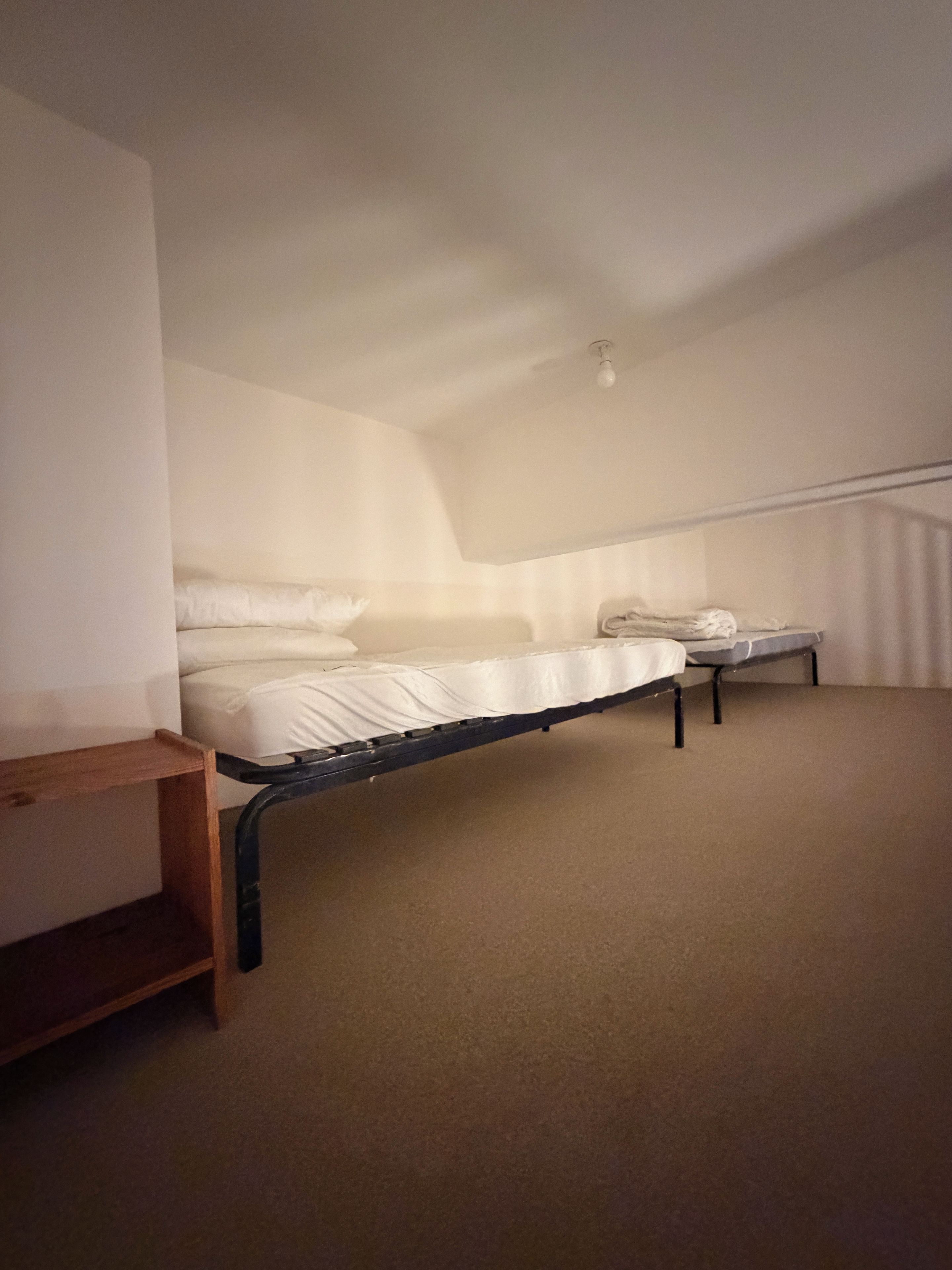 A bedroom with a single bed, a small table, and a sloped ceiling.