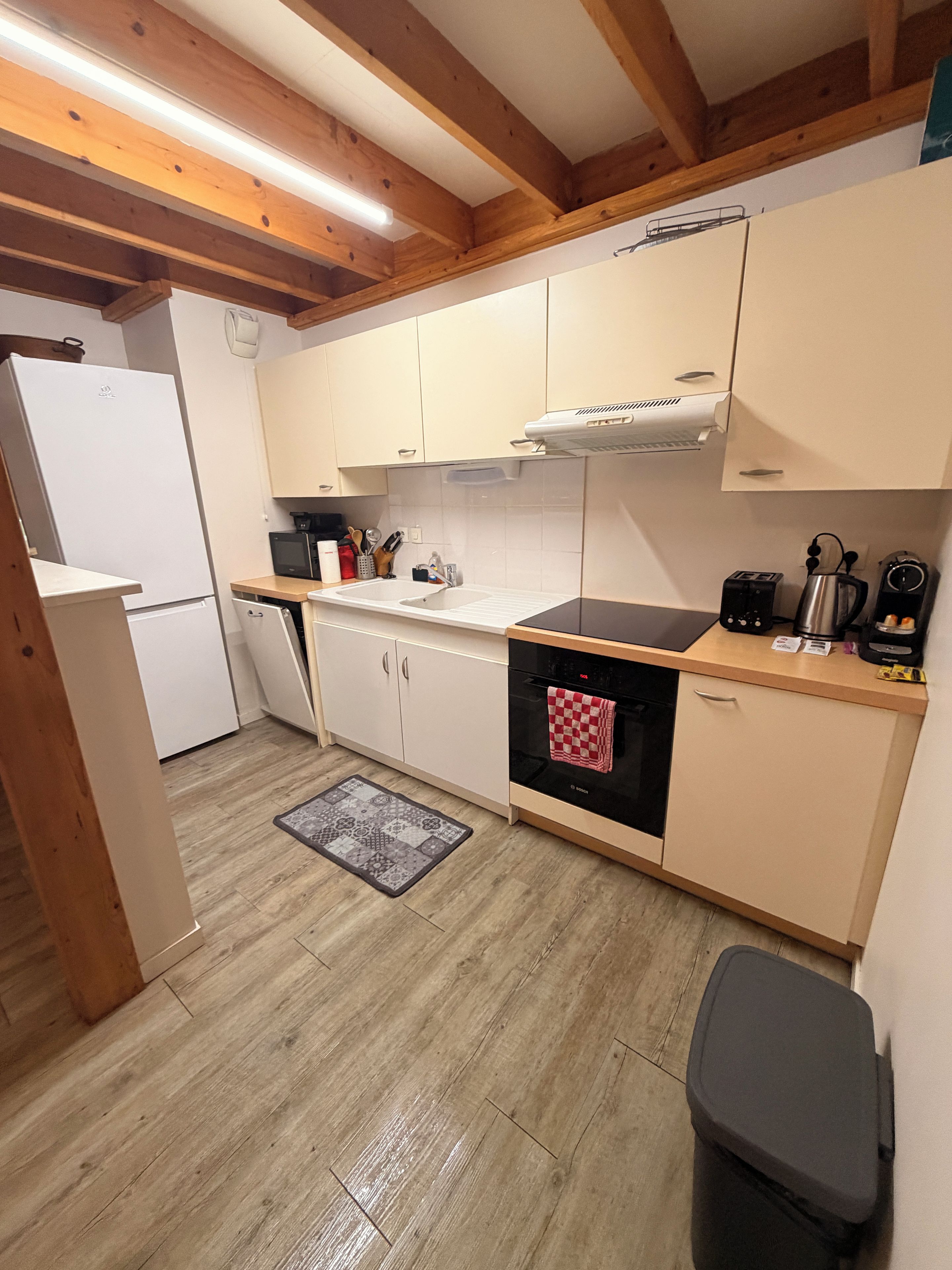 Una cocina compacta con refrigerador, estufa, lavamanos y gabinetes.
