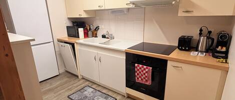 Una cocina compacta con refrigerador, estufa, lavamanos y gabinetes.