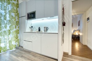 A modern kitchen with white cabinets, a built-in microwave, and a coffee maker.