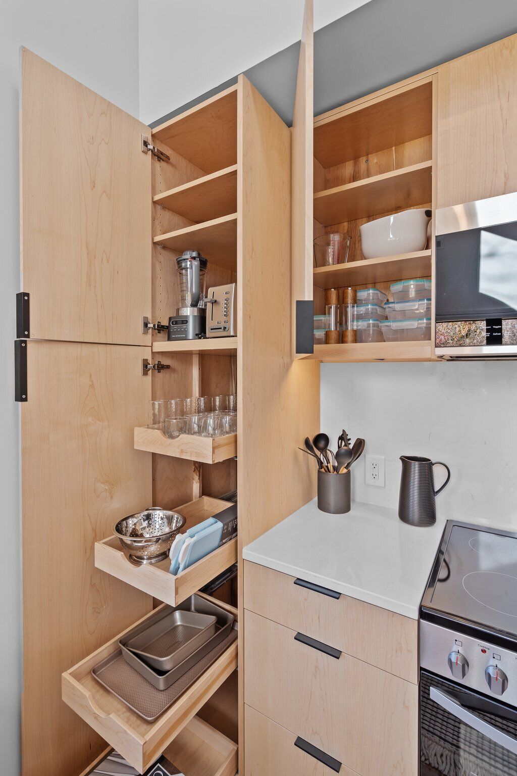 Una cocina compacta con armarios de madera, horno empotrado y encimera con tetera y utensilios.