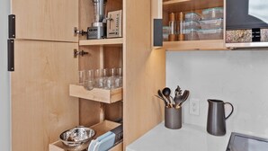 Una cucina compatta con mobili in legno, forno integrato e un piano di lavoro con bollitore e utensili.