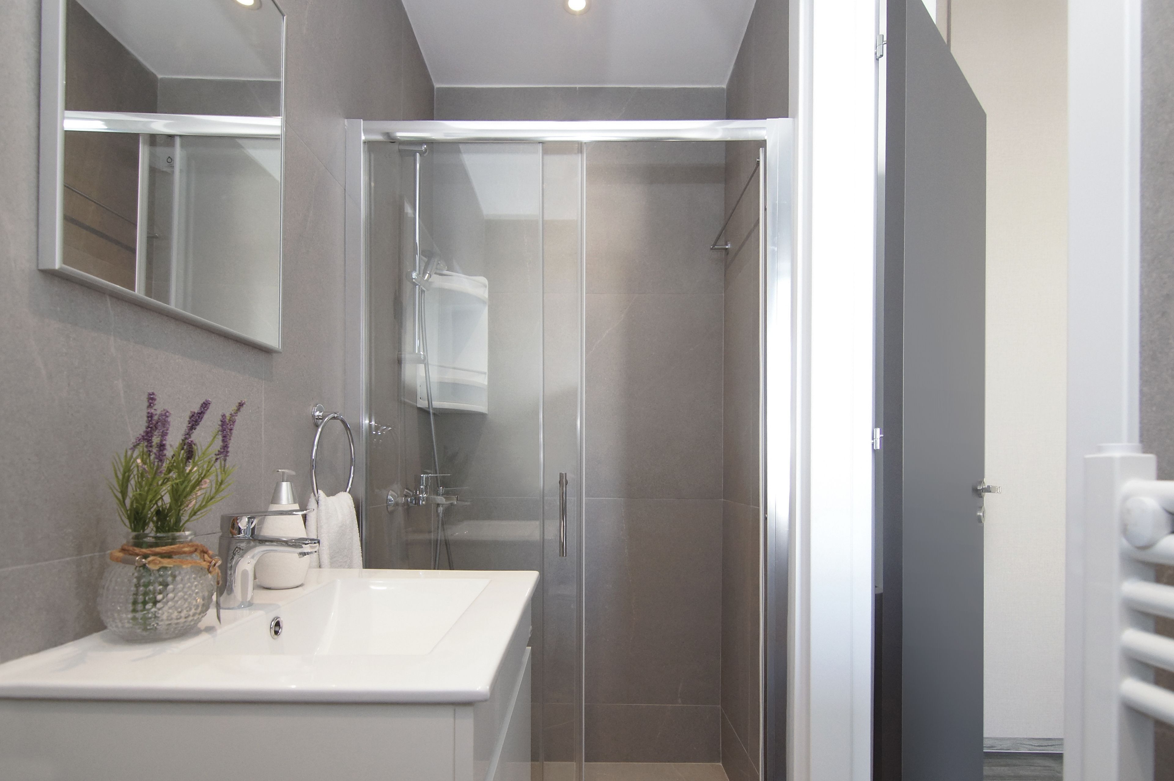Une salle de bain moderne avec une douche à parois de verre, un lavabo blanc et un miroir.