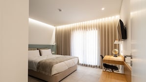 A modern hotel room with a large bed, a desk with a globe, and a TV mounted on the wall. - Be Alva (Oliveira do Hospital)
