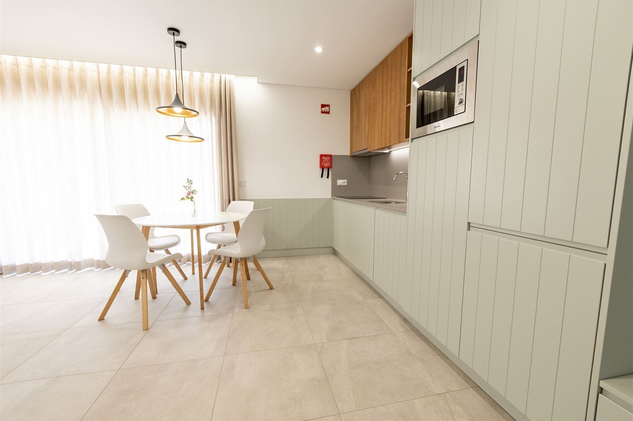 A modern kitchen with white cabinets, a built-in microwave, and a dining area with a round table and chairs.