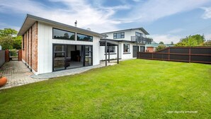 A modern two-story house with a large backyard, a covered patio, and a fenced area. - Spacious, modern, centrally located house. (Geraldine)