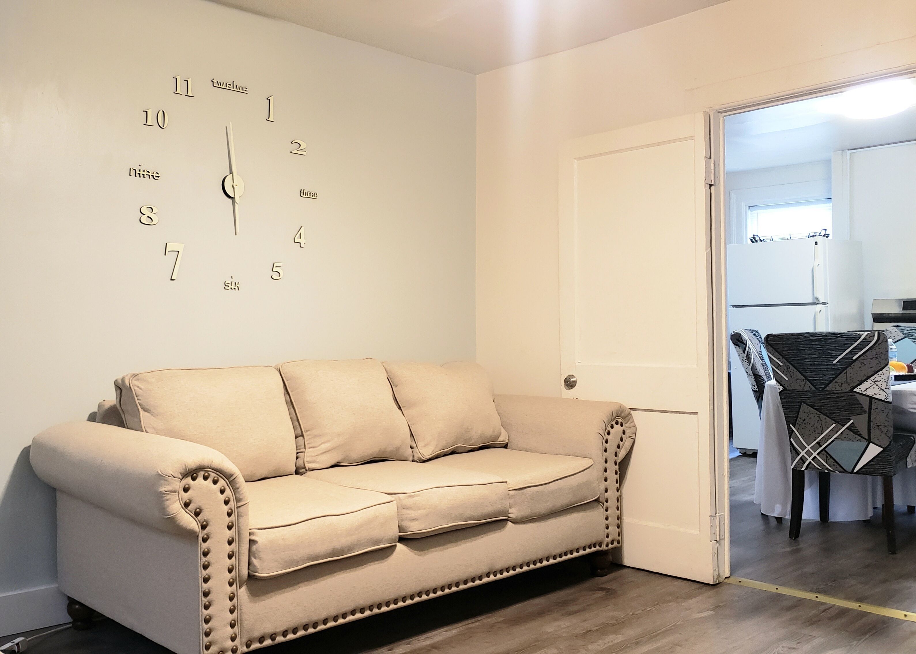 Een beige bank met decoratieve stiksels en een wandklok.