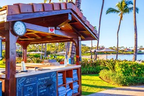 A wooden structure with a clock and an AED sign, surrounded by palm trees and a beach view. - Wailea Beach Villas Resort by KBM (Kihei)