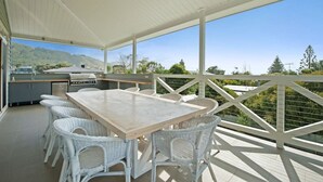 Eine Terrasse im Freien mit Tisch, Stühlen, einem Grill und Blick auf die umliegende Landschaft.
