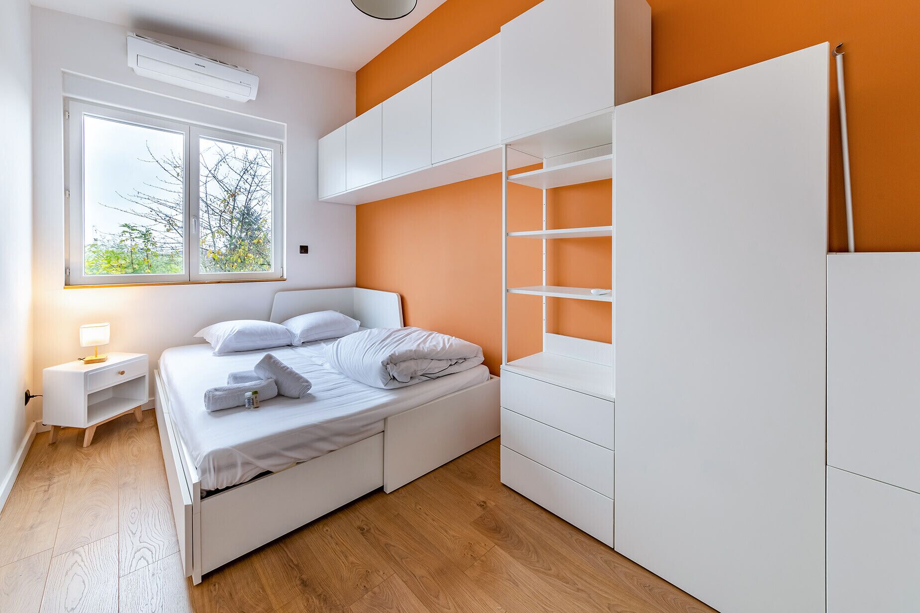 Ein Schlafzimmer mit einem Bett, einem weißen Kleiderschrank und einem Nachttisch mit einer Lampe.