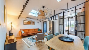 Un salon moderne avec une table à manger en bois, un canapé et une grande fenêtre agrémentée de rideaux.