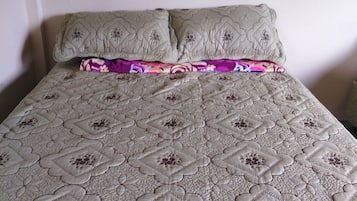 A bed with a patterned quilt and two pillows.