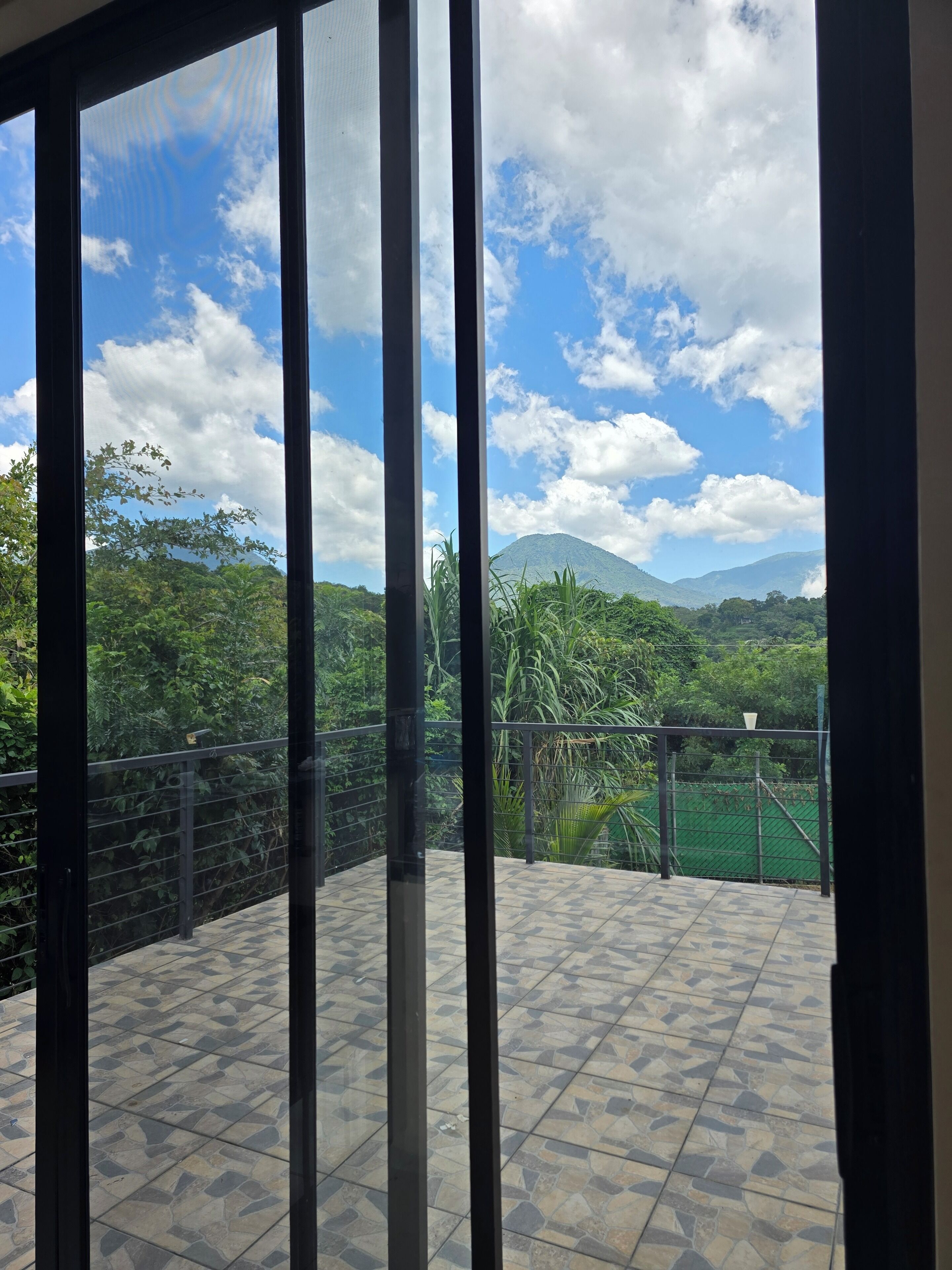 A balcony with a view of a mountain and greenery.