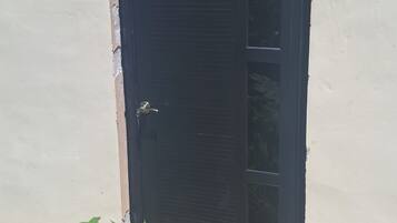 A closed door with a metal handle, set in a plain wall with a stone-tiled ground.