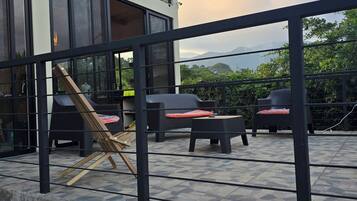 A modern outdoor seating area with wicker furniture and a view of mountains.