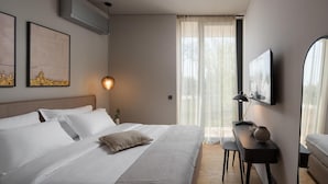 A hotel room with a large bed, a desk with a lamp, a TV on the wall, and a window with sheer curtains. - Beautiful home in Vodnjan with sauna (Vodnjan)
