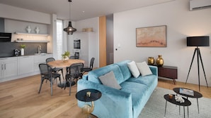A modern living room with a blue sofa, a dining area with a wooden table, and a kitchen with white cabinets. - Beautiful home in Vodnjan with sauna (Vodnjan)
