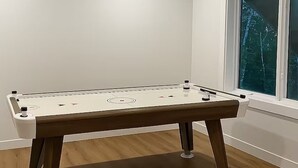 A foosball table in a room with wooden flooring and a window with a view of trees. - gsfasdrggg (Tobermory)