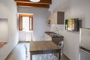 A modern kitchen with a wooden table and chairs, a built-in stove, and a TV mounted on the wall.