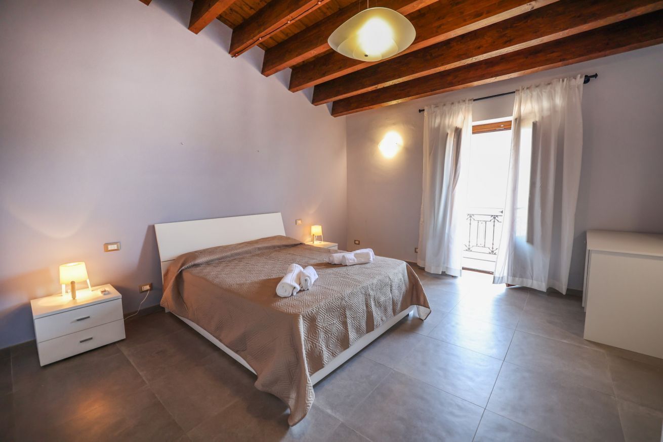 Ein Schlafzimmer mit Bett, Nachttischen, einer Lampe und Blick ins Freie.