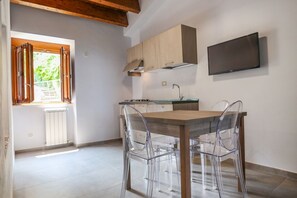 Eine moderne Küche mit einem Holztisch, klaren Stühlen, einem eingebauten Ofen und einem an der Wand montierten Fernseher.