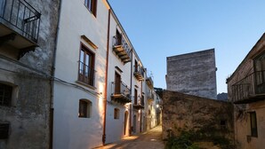 A narrow street with buildings featuring balconies and arched windows.