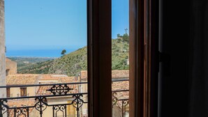 Un balcón con vista a un paisaje costero, que incluye edificios escalonados y una colina.