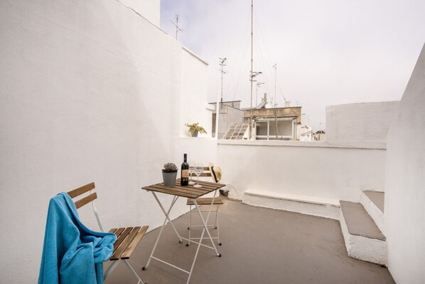 Un pequeño patio al aire libre con una mesa de madera, una silla y una toalla azul.